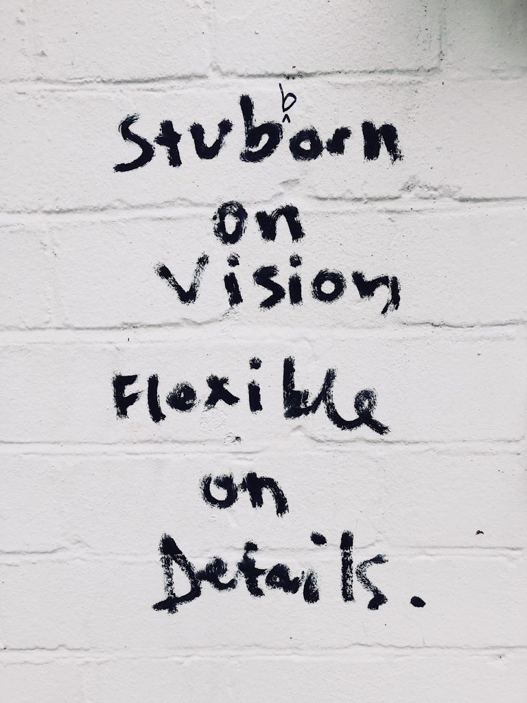 A writing on a wall that says "stubborn on vision, flexible on details".